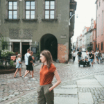Young lady walking on brick paved street with old style buildings and vacationers in background