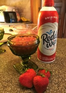 Rhubarb Tapioca Pudding in green glass dessert cup with fresh strawberries in foreground and Reddi Wip can in background
