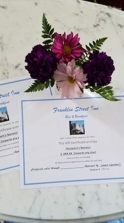 2 gift certificates for inn on table with flowers