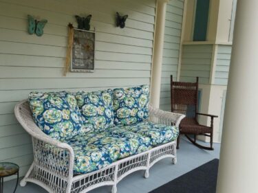porch with white wicker sofa and brown wicker rocker