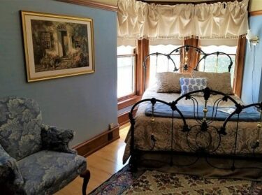 Iron bed set in turret of windows in Rhodes Room