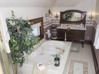 bathroom with bubble bath, wine perched on side of tub, sink in antique furniture