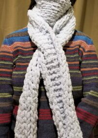 person's neck wrapped with white crocheted scarf